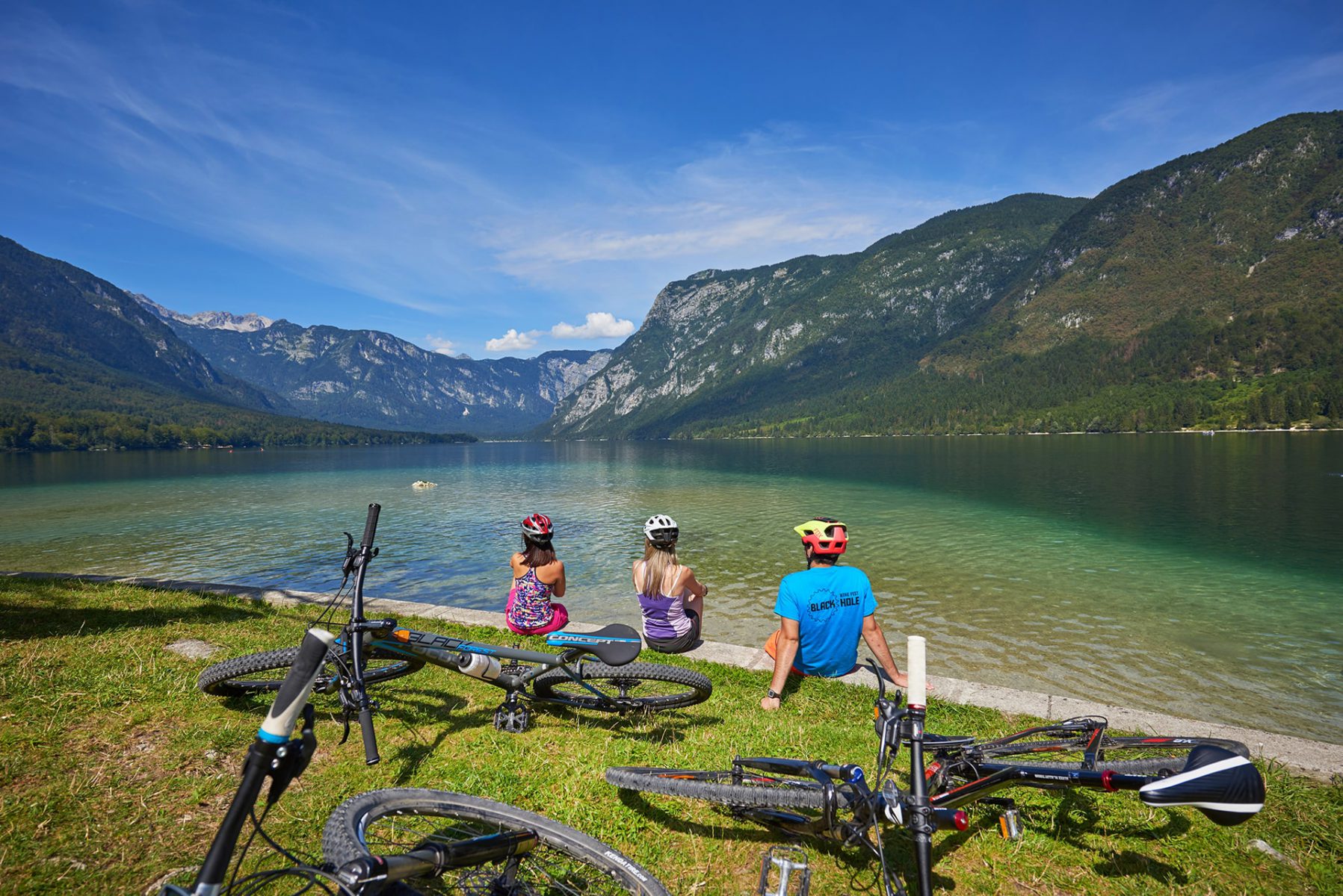 Pyöräilijöitä istuskelemassa Bohinj-järven rannalla Sloveniassa.