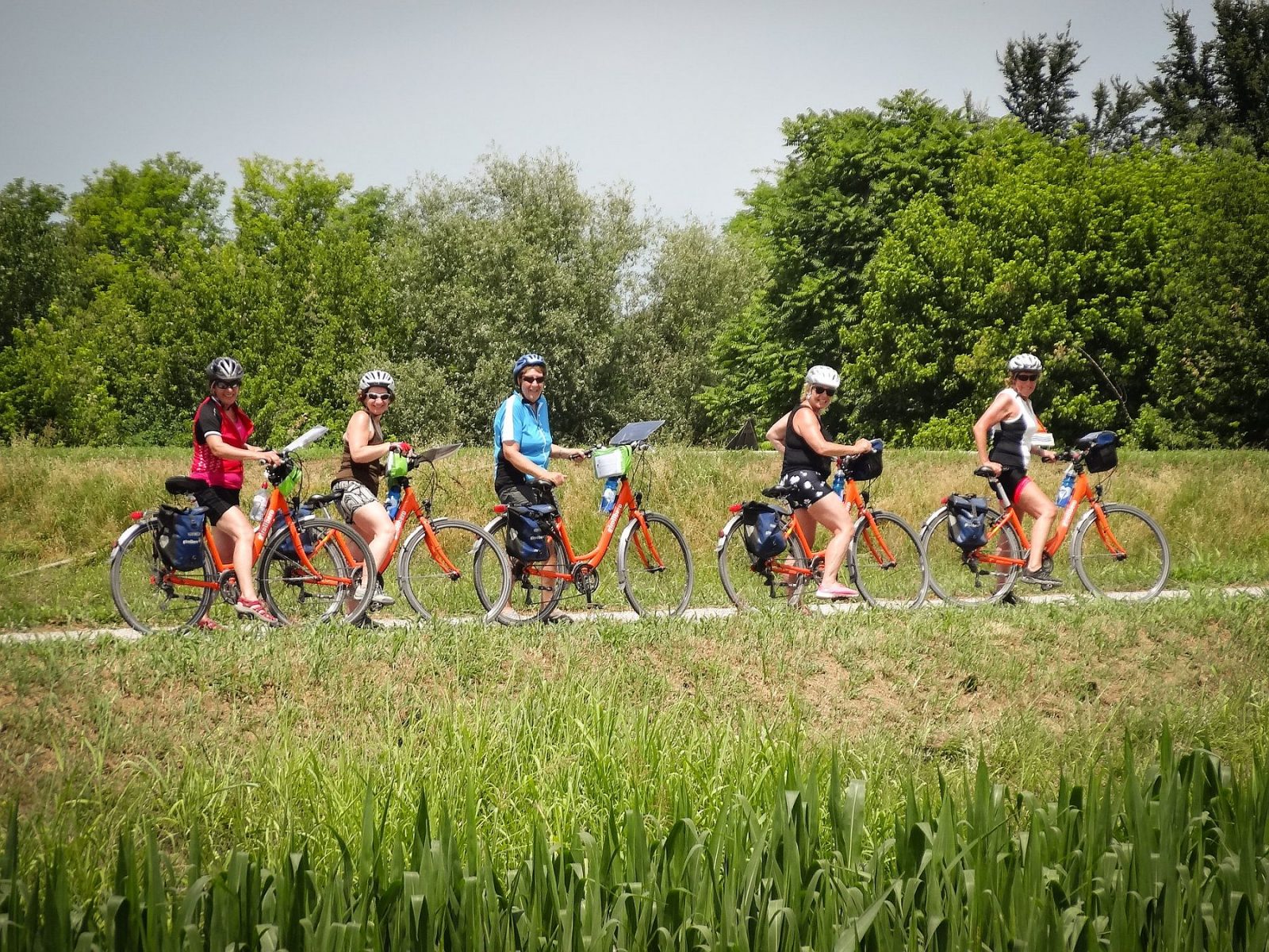 Ryhmä iloisia pyöräileviä naisia on pysähtynyt pyörätielle jonoon.