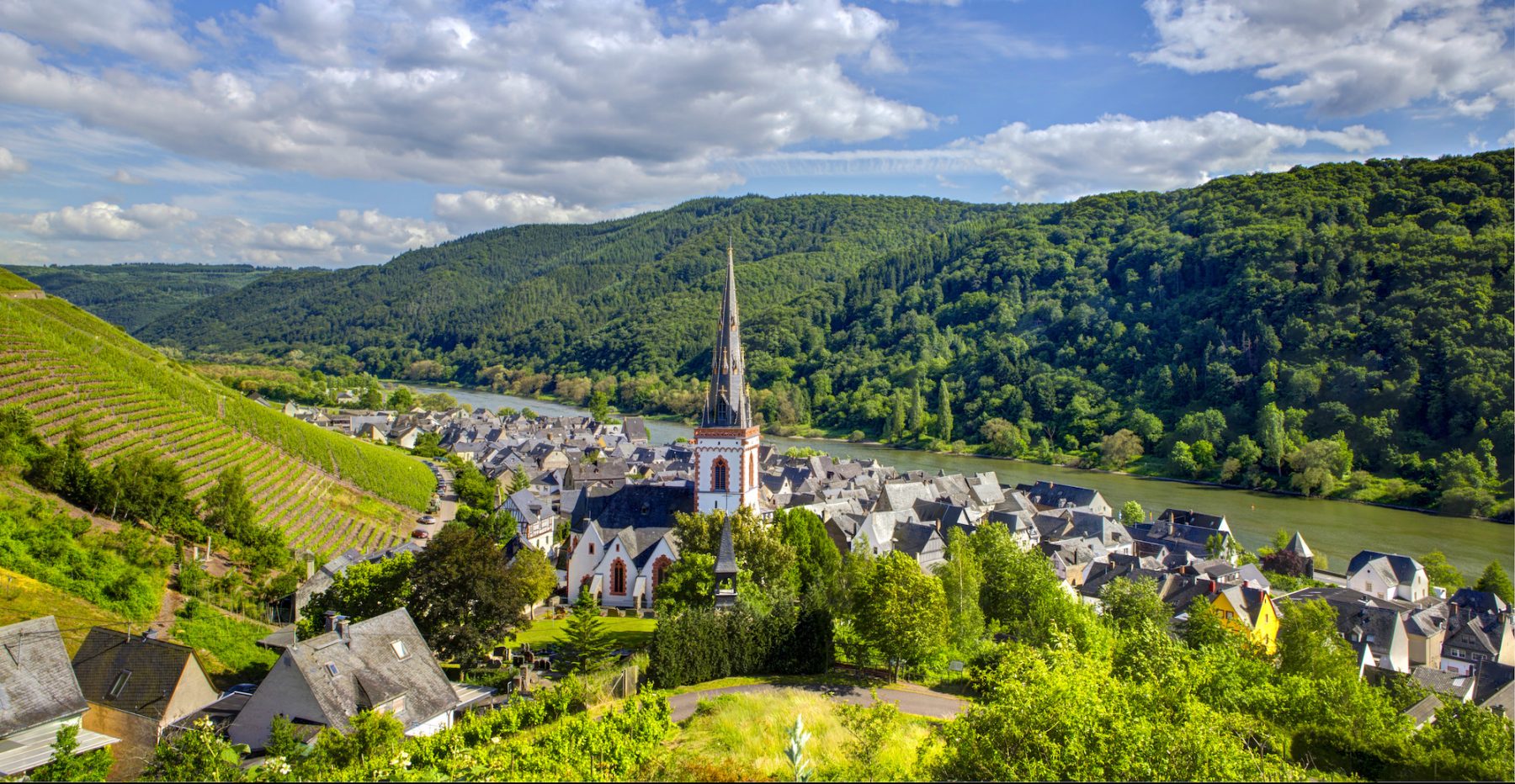 Kylä ja kirkontorni Moselin rannalla.