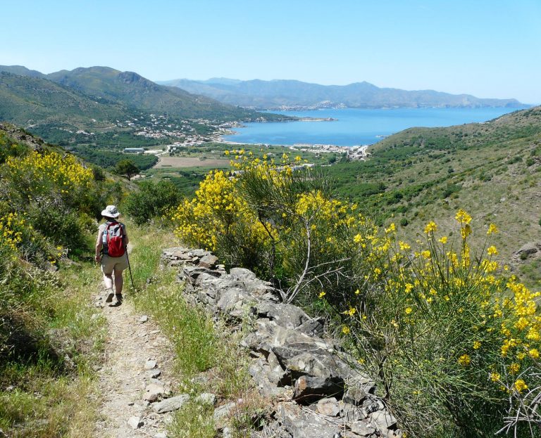 Vaeltaja lähestyy Cadaquesia alamäkeen viettävällä polulla.