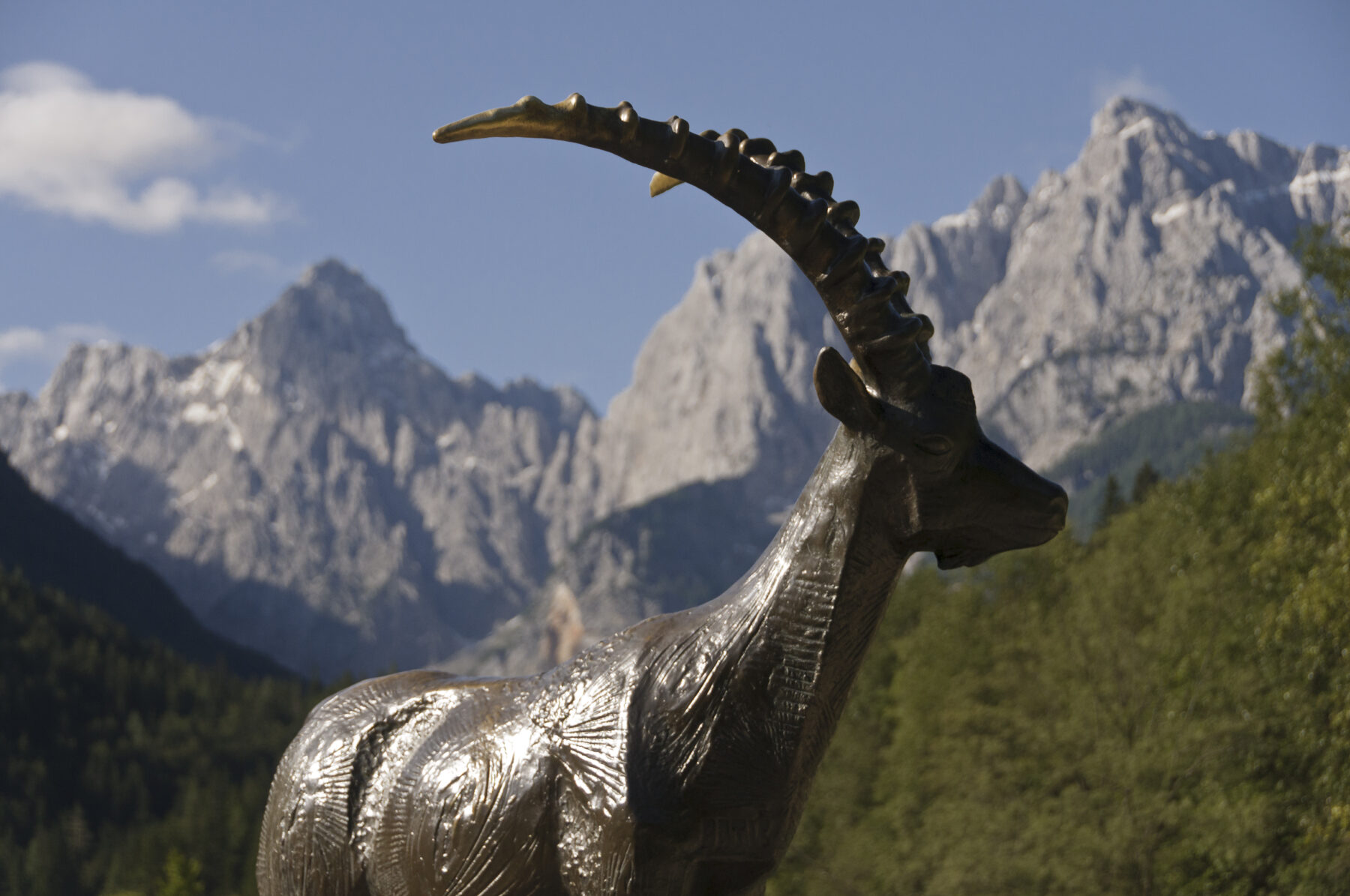 Vuorikauris patsas, jonka taustalla kohoavat teräväpiirteiset vuoret.